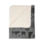 Folded Vermont blanket corner showing the cream-colored sherpa underside and gray printed front