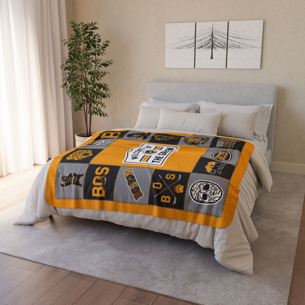 Gold, black and gray Boston hockey fleece blanket displayed across a bed
