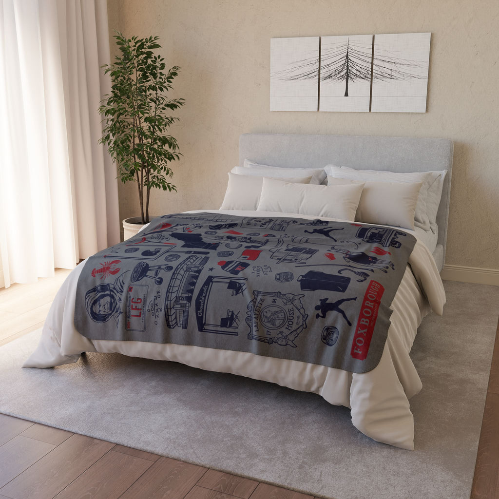 Gray Foxboro football fleece blanket displayed across a bed with navy and red illustrated details