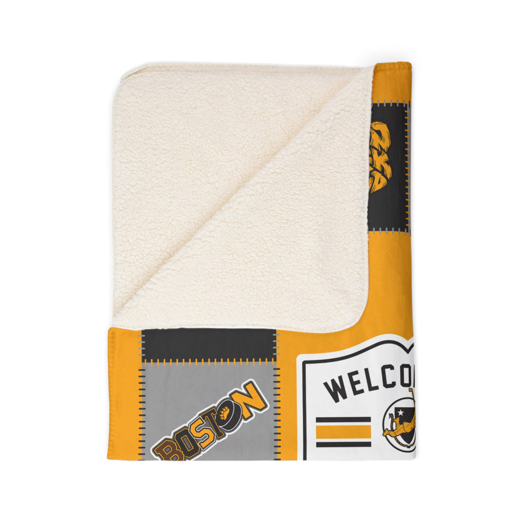 Folded Boston hockey blanket showing cream sherpa underside and gold-and-black print