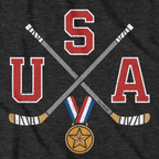 Close-up of charcoal USA Cross Sticks shirt design — crossed sticks and flag detail