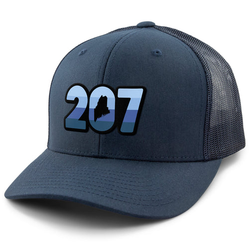 Three-quarter front view of a navy Retro 207 Maine snapback trucker hat with blue-striped numbers and a state silhouette in the zero