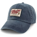 Angled front view of navy washed dad hat with cream Maine patch, red script and state silhouette